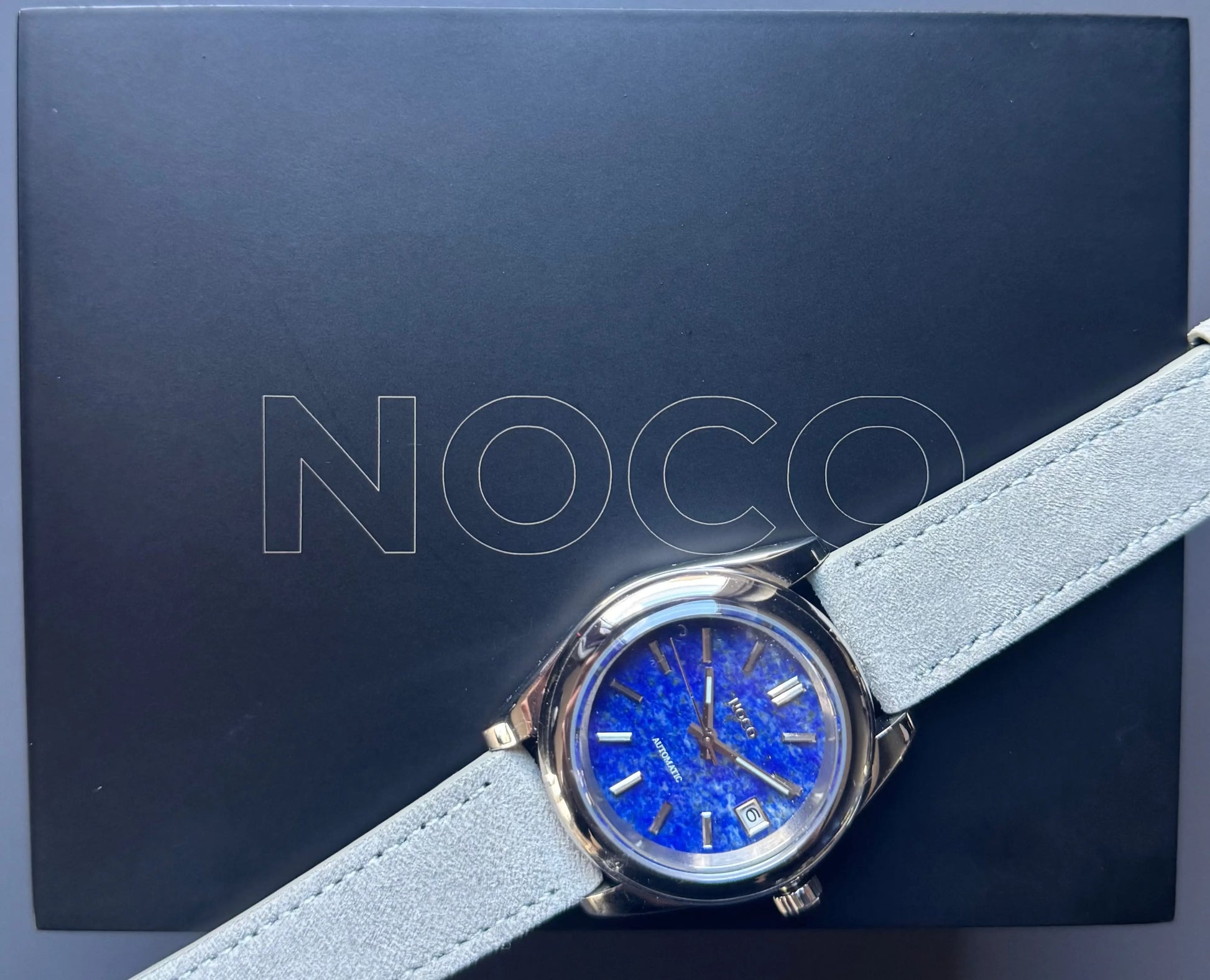 Montre Noco Watches présentée sur sa boîte, mettant en valeur le cadran en pierre de lapis-lazuli